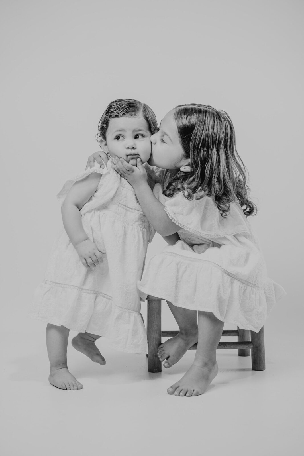 Dos hermanas dándose un beso en la sesión