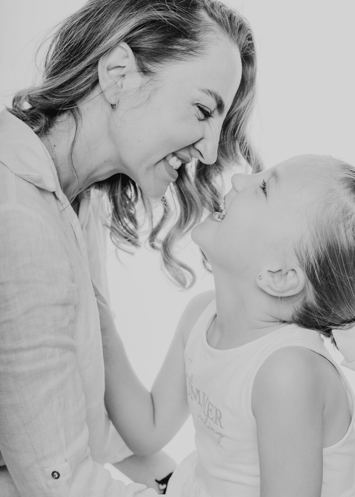 Mamá e hija riendo juntas durante la sesión de familia