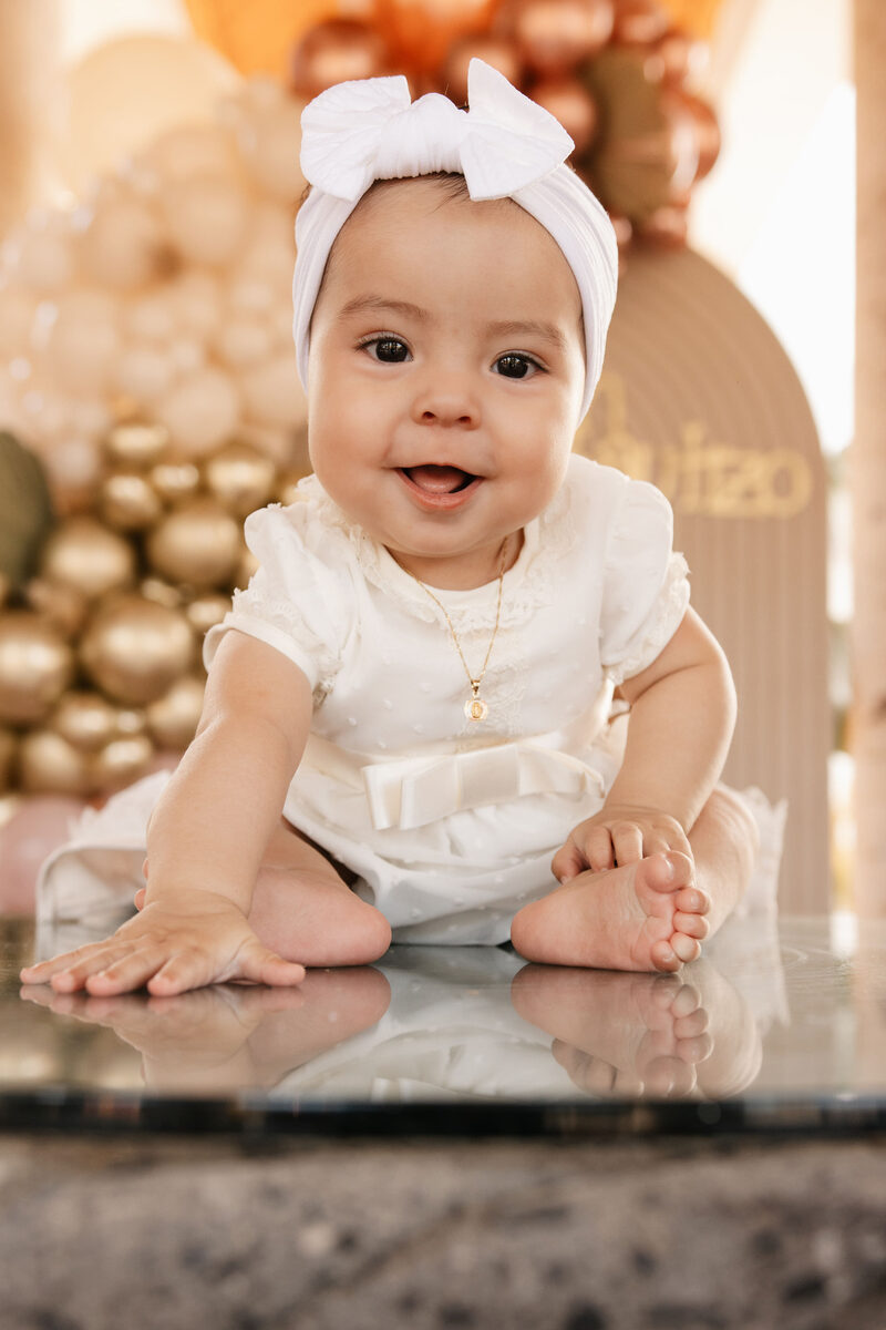 Bebé sonriendo con diadema de moño, festejo de bautizo
