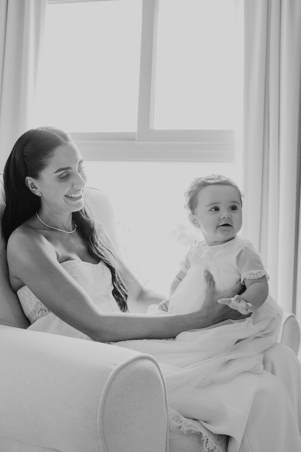 Mamá y su bebé junto a la ventana el día del bautizo, fotografía en blanco y negro